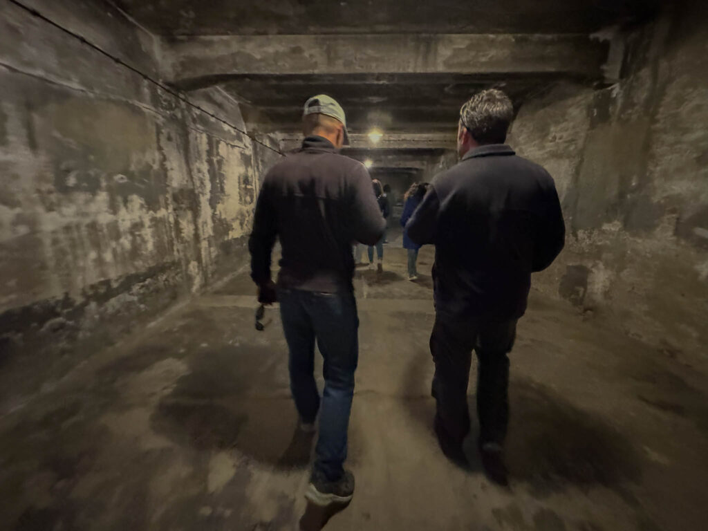 Walking through the gas chamber at Auschwitz I. The dimly lit, concrete-walled chamber has a low ceiling and a worn, rough interior, reflecting its tragic past. This space was used by the Nazis for mass executions using Zyklon B, and today it stands as a stark reminder of the atrocities committed during the Holocaust.