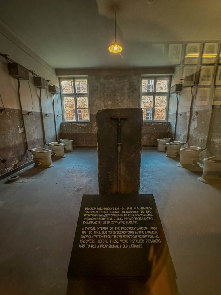 This image shows the prisoners’ latrine at Auschwitz I, highlighting the extremely poor sanitation conditions. A sign explains that due to severe overcrowding, these facilities were inadequate for all prisoners, and before their installation, inmates had to rely on provisional field latrines.