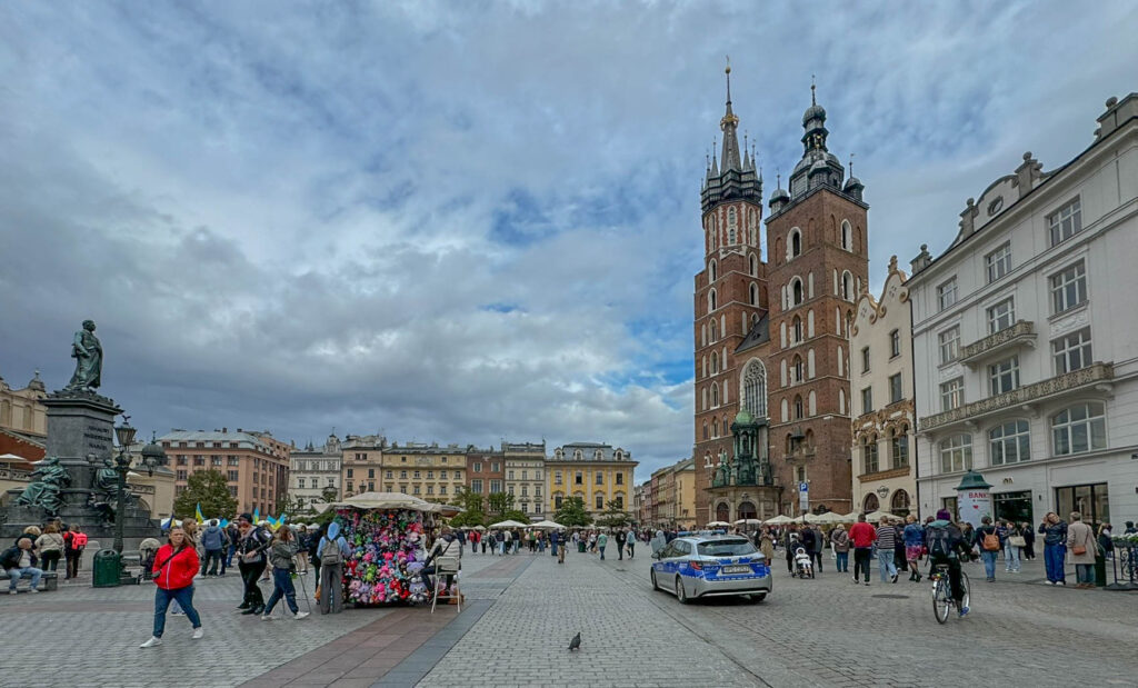 The statue on the left is the Adam Mickiewicz Monument (Pomnik Adama Mickiewicza), dedicated to Poland’s most famous Romantic poet, Adam Mickiewicz. Unveiled in 1898, the monument stands in Kraków’s Main Market Square (Rynek Główny) and is a popular meeting spot for both locals and tourists. The building on the right is St. Mary's Basilica (Kościół Mariacki), one of Kraków’s most famous landmarks, known for its twin towers of different heights and stunning Gothic architecture. Inside, it houses the world-renowned Veit Stoss altarpiece, and every hour, a bugler plays the Hejnał Mariacki, a historic trumpet call from the taller tower.