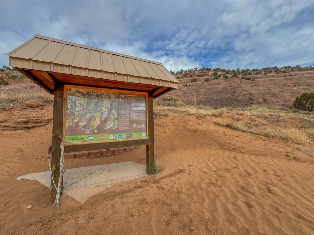 The official start of the Church Rock Trail, marked by a sand-dusted kiosk and a weathered map. This 2.4-mile loop winds through Navajo sandstone and slickrock shelves, offering sweeping views and a close encounter with the iconic Church Rock formation.