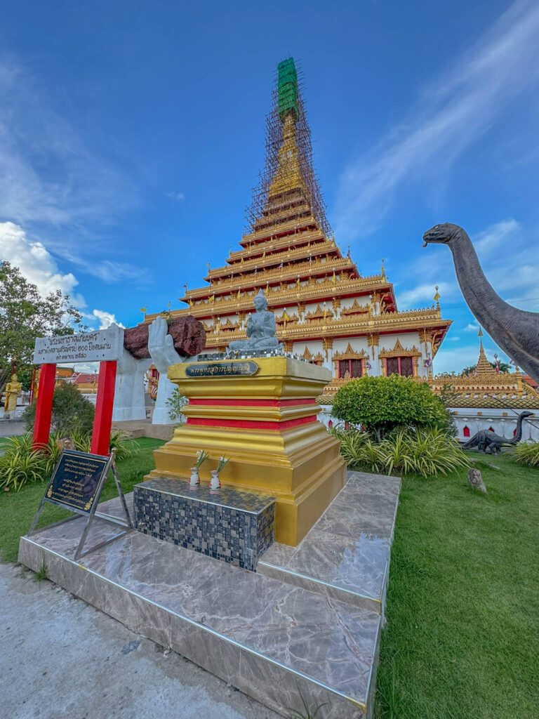 A Buddha statue, a dinosaur with lotus flowers in its mouth, and giant hands holding a log. Sure, why not.