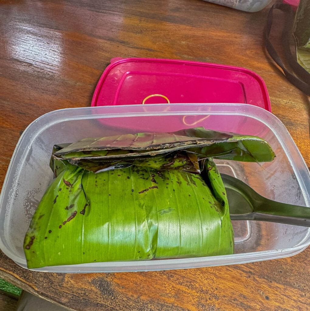 A still-warm breakfast of fried rice and a hard-boiled egg wrapped in a banana leaf.